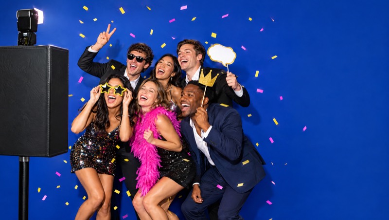 Freunde feiern mit Konfetti und Requisiten vor der Fotobox